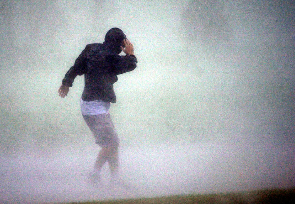 FILE - In this Thursday, Oct. 3, 2002, file photo, taken by Dave Martin, Jeff Gammons tries to walk against the wind and rain of Hurricane Lili as it neared landfall near New Iberia, Louisana. Martin, a longtime Associated Press photographer based in Montgomery, Ala., died after collapsing on the Georgia Dome field at the Chick-fil-A Bowl on Tuesday, Dec. 31, 2013. Martin was 59. (AP Photo/Dave Martin, File)