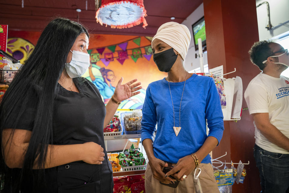 Rep. Ilhan Omar, center, D-Minn., talks with Dulce Sanchez, whose family owns Dulceria La Piñata at Mercado Central in Minneapolis, on Tuesday, Aug. 11, 2020, primary day in the state. Omar faces Antone Melton-Meaux in the Democratic primary, (Leila Navidi/Star Tribune via AP)