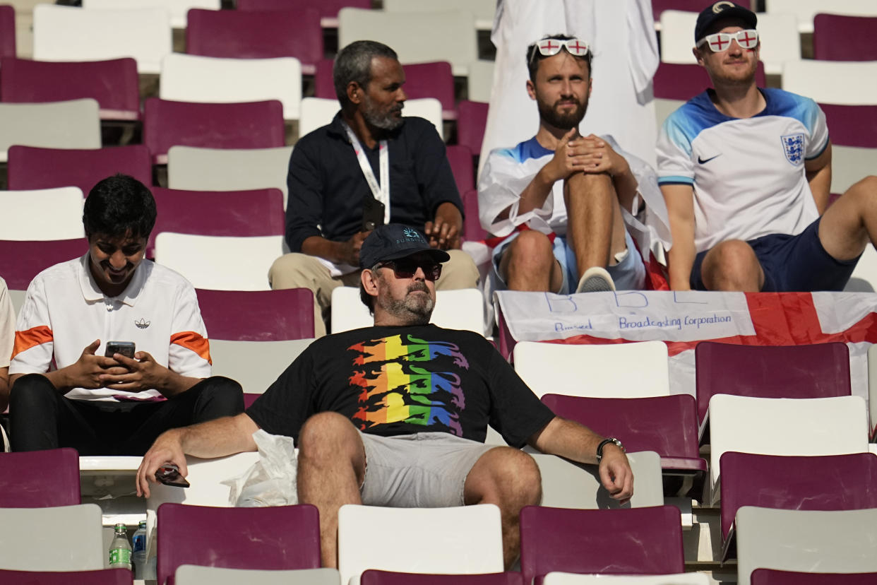 An England fan wearing a rainbow shirt sits in the stands prior to the start of the World Cup group B soccer match between England and Iran at the Khalifa International Stadium in in Doha, Qatar, Monday, Nov. 21, 2022. (AP Photo/Abbie Parr)