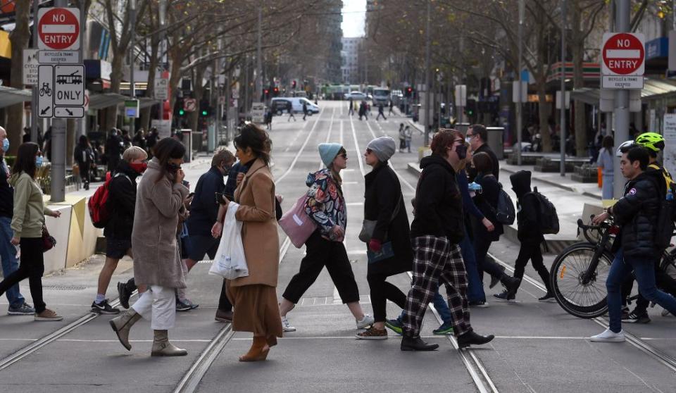 People walk across a street in Melbourne.