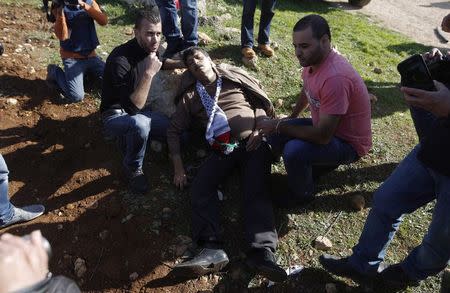 Palestinian minister Ziad Abu Ein (C) falls after being hit by Israeli soldiers during a protest near the West Bank city of Ramallah December 10, 2014. REUTERS/Mohamad Torokman