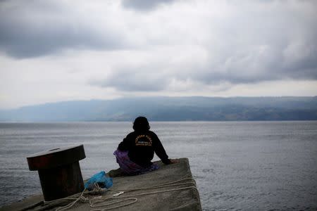 Kamel Purba, a farmer who lost his mother and brother in the ferry accident at Lake Toba, sits on a pier of Tigaras port in Simalungun, North Sumatra, Indonesia June 21, 2018. REUTERS/Beawiharta