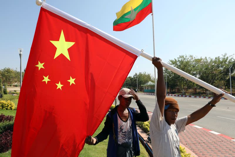 Workers put up flags a day before Chinese President Xi Jinping's visit to Myanmar in Naypyitaw