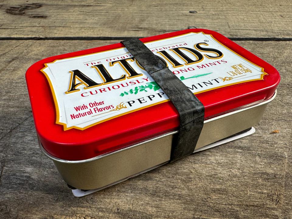 Rubber band is secured around an Altoids tin.