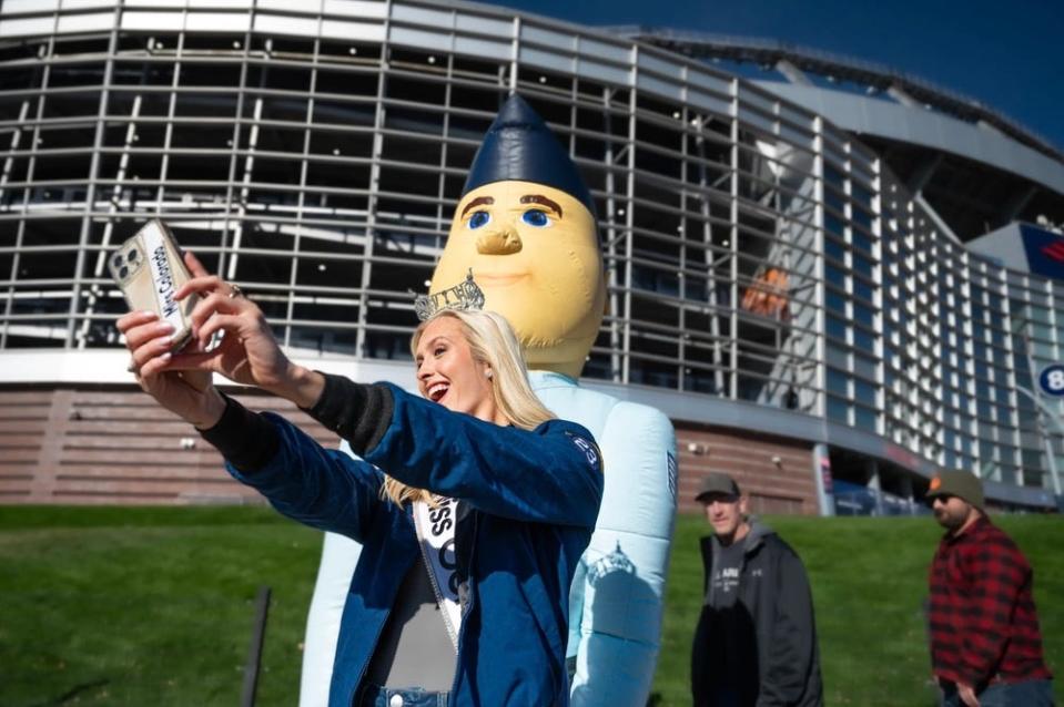 a woman wearing a crown takes a selfie with an inflated soldier