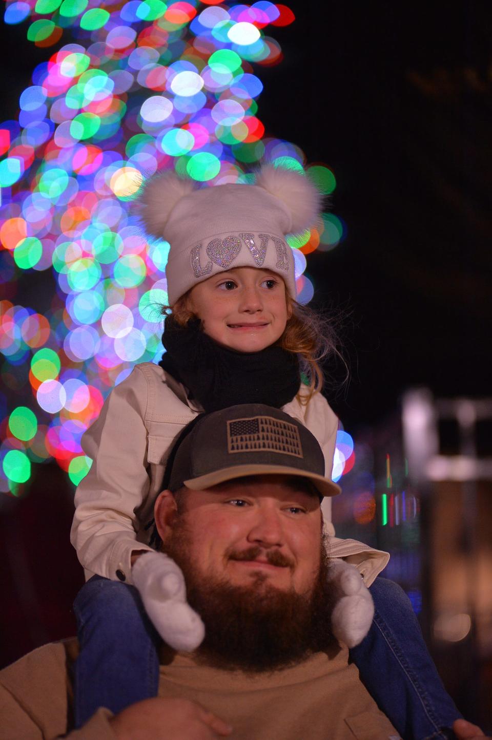 The City of Spartanburg held the 27th annual "A Dickens of a Christmas" in downtown Spartanburg, Tuesday evening, December 7, 2021. The victorian-themed holiday event included live Christmas music, window displays, horse-drawn carriage rides, and the lighting of the Christmas tree at Denny's Plaza. Holden Guffey holds his daughter Emma, 4, on his shoulders in front of the lit Christmas tree.