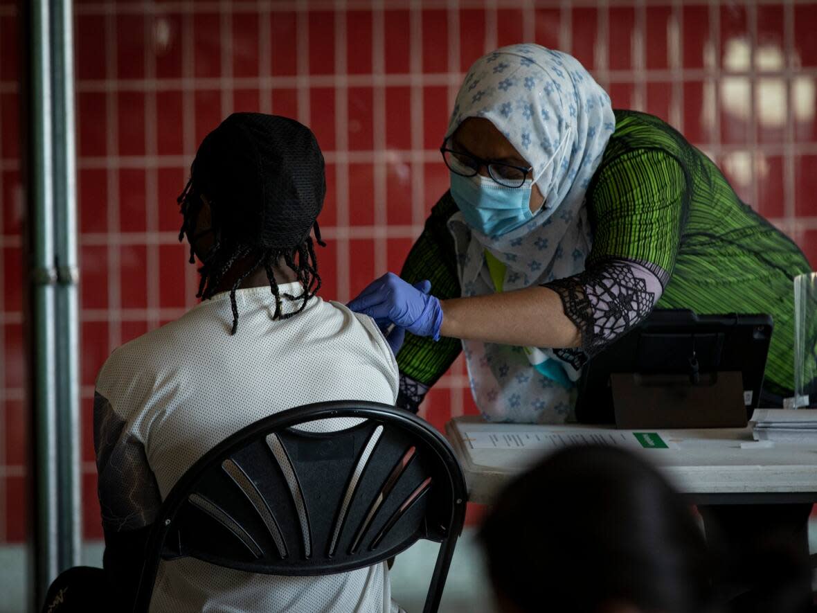 A health-care provider with East Toronto Health Partners is seen here administering a COVID-19 vaccine dose at a pop-up clinic in Toronto's Victoria Park station last August. (Evan Mitsui/CBC - image credit)