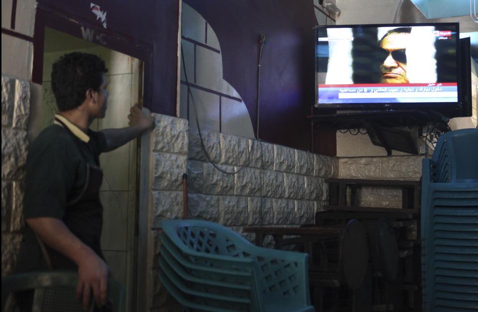 FILE - In this June 2, 2012 file photo, a worker in a downtown cafe watches the final session of the trial of former Egyptian President Hosni Mubarak, in Cairo, Egypt. The 2011 uprising led to the quick ouster of autocrat Mubarak. A decade later, thousands are estimated to have fled abroad to escape a state, headed by President Abdel Fattah el-Sissi, that is even more oppressive. (AP Photo/Thomas Hartwell, File)