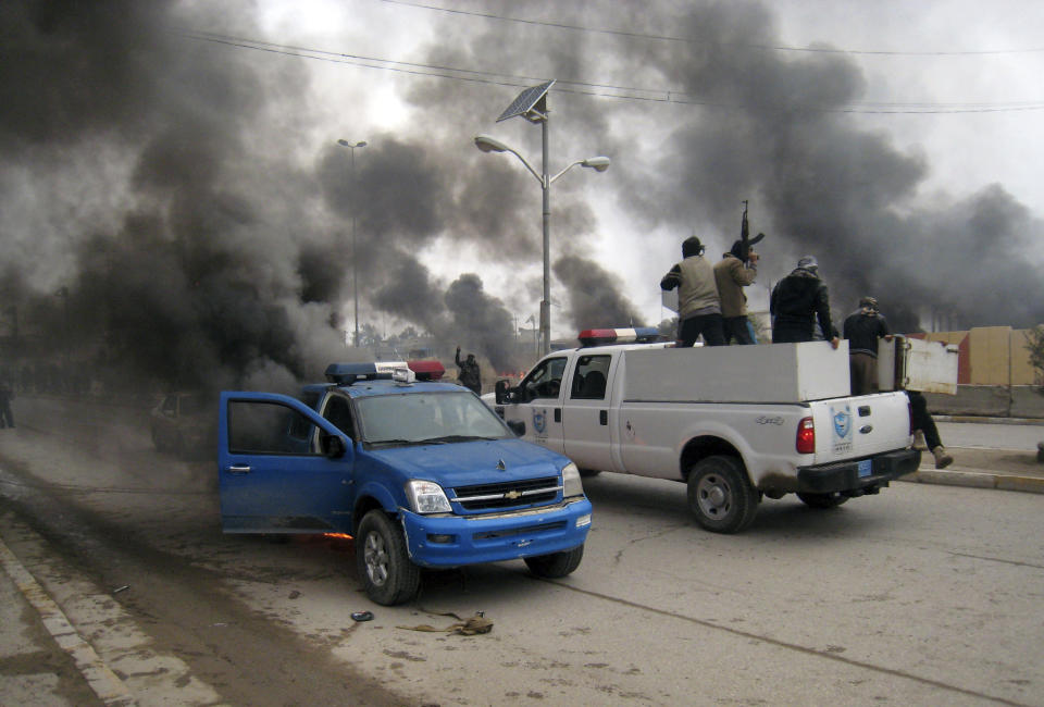 FILE - In this Wednesday Jan. 1, 2014, file photo, al-Qaida fighters patrol in a commandeered police truck passing burning police vehicles in front of the main provincial government building in Fallujah, Iraq. More than a month after jihadist militants seized control of parts of Iraq’s western Anbar province, an unsettling realization is sinking in: Iraq’s government could face a tougher time beating back an insurgency there than the hard slog the Americans faced last decade. The reasons include a deep distrust of the government by Iraqi Sunnis, insufficient resources, sectarian tensions enflamed by the war in Syria and divisions among the tribes that make up Anbar’s social fabric. (AP Photo, File)