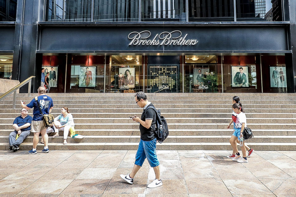 <p>A man uses his mobile device while others sit on the steps outside Brooks Brothers as people check out construction at the World Trade Center site in New York City on Aug. 18, 2018. (Photo: Gordon Donovan/Yahoo News) </p>