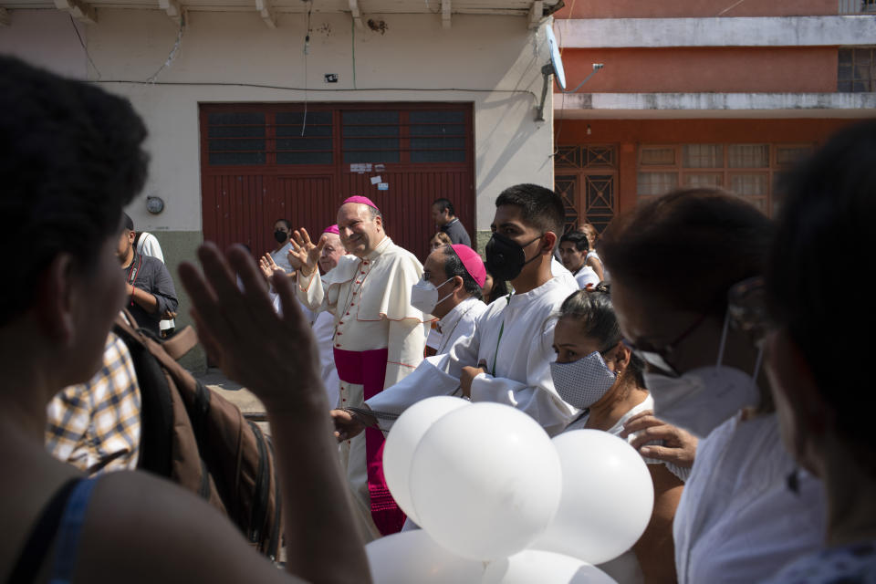 Monsignor Franco Coppola, the Vatican's diplomat to Mexico, greets people as he arrives to meet families and celebrate Mass in Aguililla, a town that has been cut off by warring cartels in Michoacan state, Mexico, Friday, April 23, 2021. State police and soldiers were sent in to restore order earlier this month, but cartels responded by parking hijacked trucks across roads to block them, as well as digging deep trenches across roadways. (AP Photo/Armando Solis)