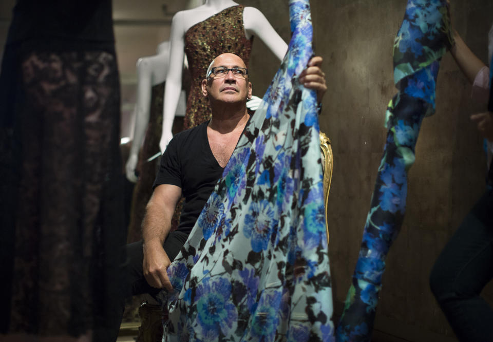 In this Aug 19, 2013 photo, fashion designer Carmen Marc Valvo sits with a bolt of fabric in his New York studio while putting together his Spring 2014 collection for a Fashion Week runway show on Sept. 6 at Lincoln Center in New York. Valvo has been at this for more than 20 years and says, "the most rewarding part of building the collection is when you make your final edit and the run of show is set in stone and no more changes can be made." (AP Photo/John Minchillo)