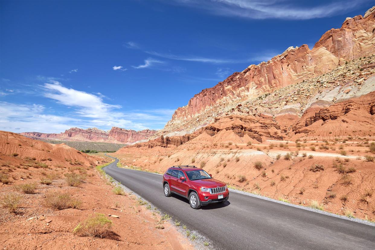 Red Jeep Cherokee driving through the desert on a sunny day.