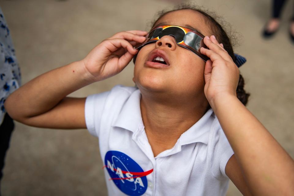 Holland Harper, 4, watches the solar eclipse during an event at the Mississippi Museum of Natural Science in Jackson on Monday. "My arms are tired," she said as she held up her glasses.