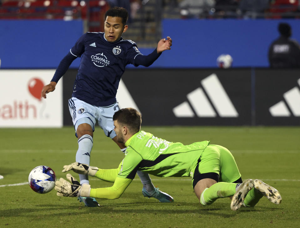 Sporting Kansas City midfielder Felipe Hernández (21) tries to score against Dallas goalkeeper Maarten Paes (30) in the second half of an MLS soccer match, Saturday, March 18, 2023, in Frisco, Texas. (AP Photo/Richard W. Rodriguez)