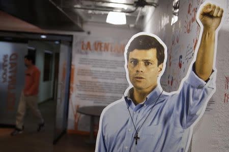 A man walks behind a cardboard figure of jailed opposition leader Leopoldo Lopez at the headquarters of political party Popular Will (Voluntad Popular) in Caracas June 5, 2014. REUTERS/Carlos Garcia Rawlins