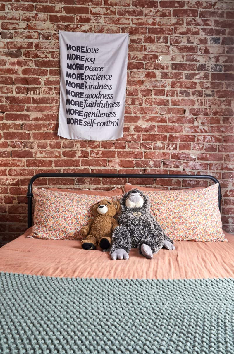 Stuffed animals on a bed with floral sheets.