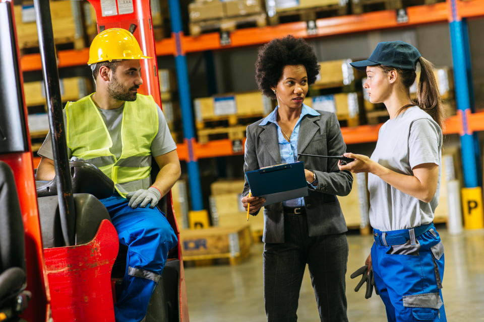 Manual worker talking with supervisor inside factory warehouse. Credit: Getty.