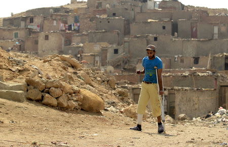 A resident of the shanty area of al-Dweiqa in Cairo walks with a crutch in this October 4, 2012 file photo. REUTERS/Mohamed Abd El Ghany/Files