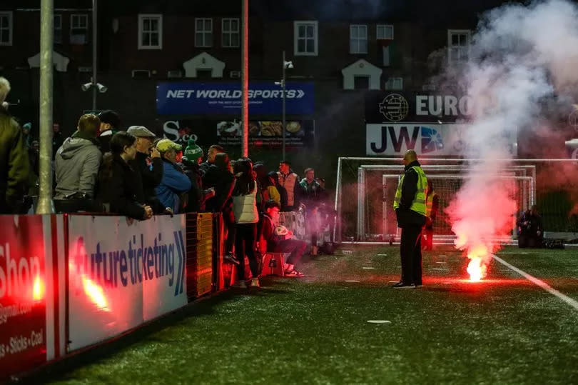 A flare lands on the edge of the pitch after it was thrown over the top of the Shamrock Rovers fans