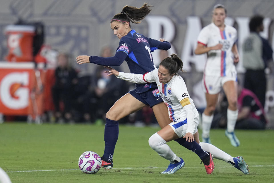 FILE - San Diego Wave forward Alex Morgan, left, controls the ball as OL Reign defender Lauren Barnes defends during the second half of an NWSL semifinal playoff soccer match Sunday, Nov. 5, 2023, in San Diego. The National Women's Soccer League has a lot to be excited about heading into its 11th season. (AP Photo/Gregory Bull, File)