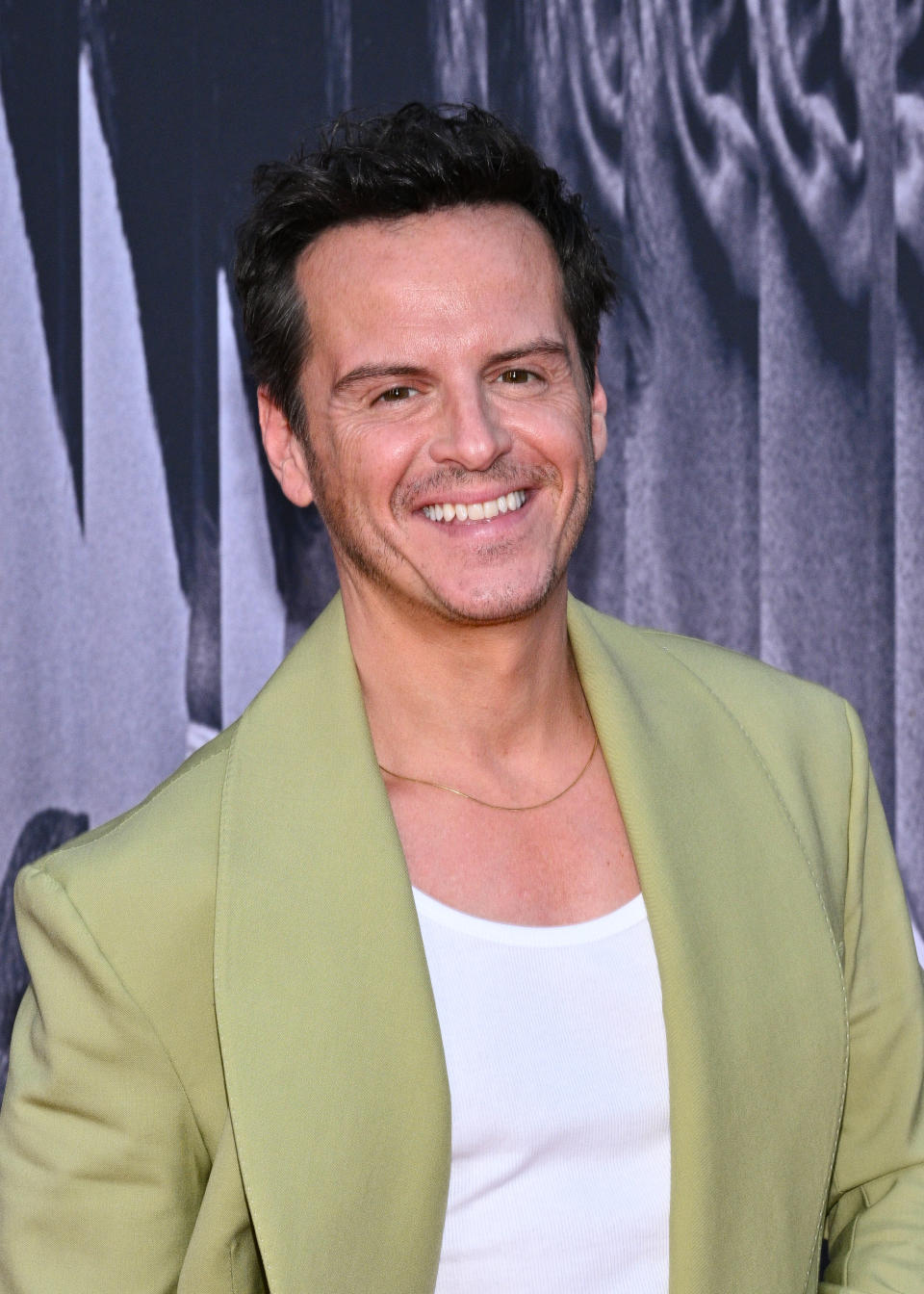 Andrew Scott is smiling at a red carpet event, wearing a shirt under a light blazer