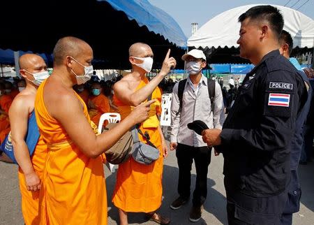 Buddhist monks speak with a policeman at the gate of Dhammakaya temple in Pathum Thani province, Thailand February 19, 2017. REUTERS/Chaiwat Subprasom