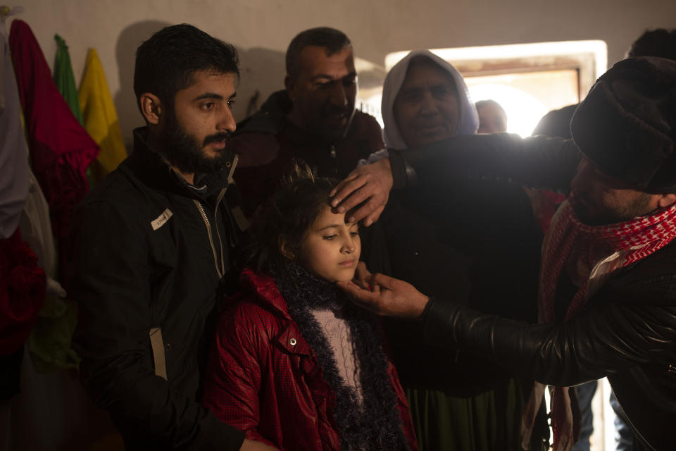 In this Feb. 12, 2020 photo, Malak Saad Dakhel, 11, is anointed by a holy man inside a Yazidi shrine as she is welcomed home by her relatives after her escape from Syria, in Sharia, Iraq. She was captured by Islamic State militants in 2014 and was recently found at al-Hol camp living with a Syrian family. (AP Photo/Maya Alleruzzo)