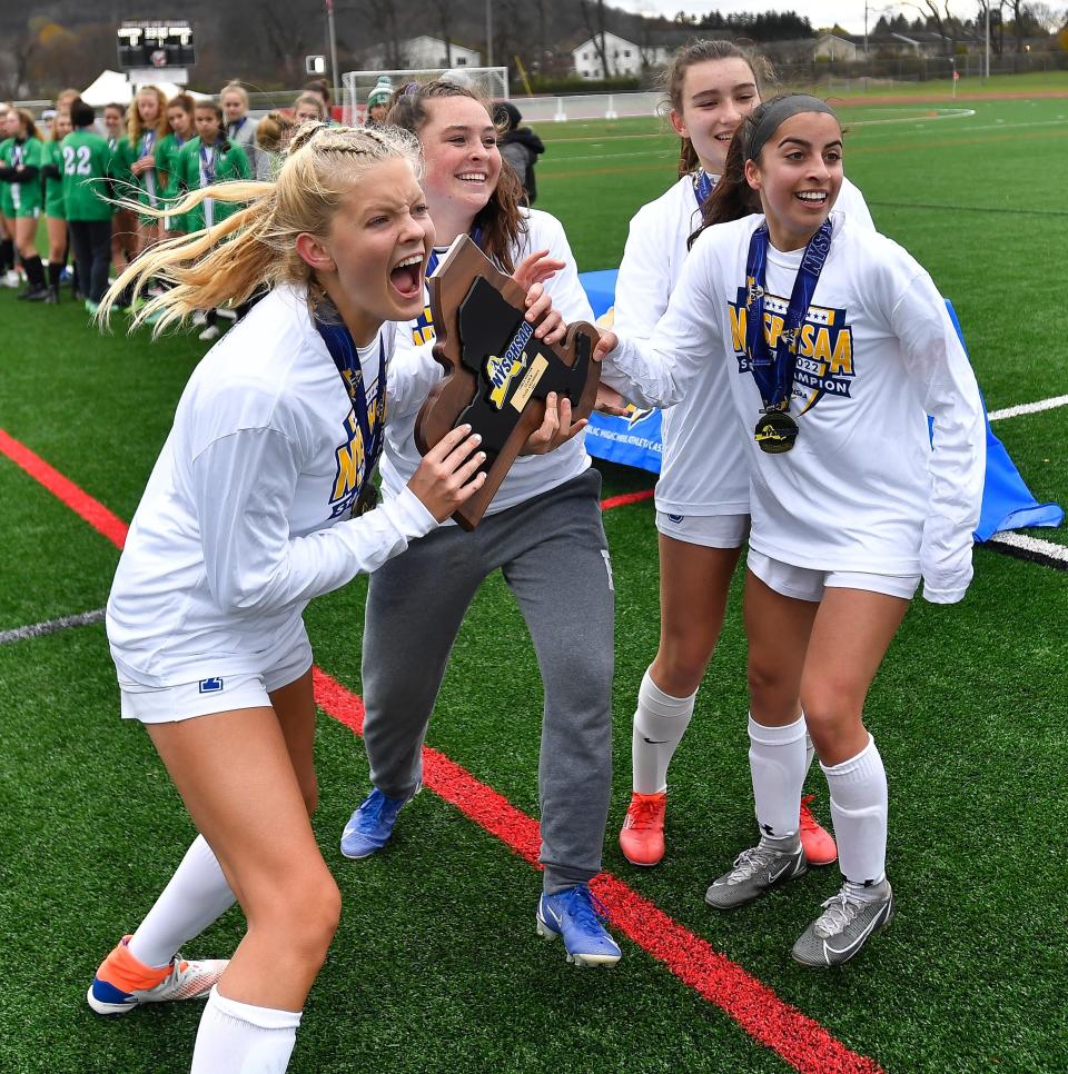 Bronxville captains celebrate with the championship plaque after beating Lewiston-Porter in the NYSPHSAA Girls Soccer Championships Class B final in Cortland, N.Y., Sunday, Nov. 14, 2021.