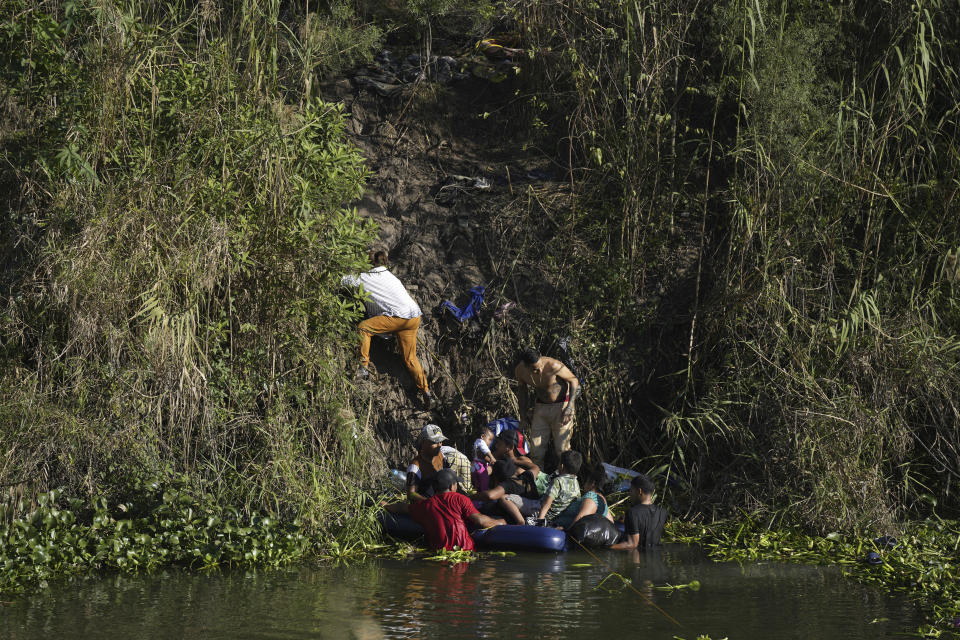 Venezuelan migrants climb onto U.S territory after crossing a river from Matamoros, Mexico, Thursday, Dec. 22, 2022. (AP Photo/Fernando Llano)