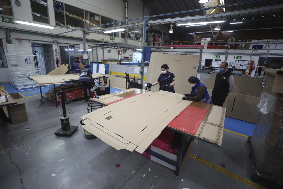 Workers at a company that designs packaging for product displays assemble a cardboard box designed to serve as both a hospital bed and a coffin, intended for COVID-19 patients, in Bogota, Colombia, Friday, May 8, 2020. Owner Rodolfo Gomez said he plans to donate the first units to Colombia's Amazonas state, and that the company will sell others to small hospitals for 87 dollars. (AP Photo/Fernando Vergara)