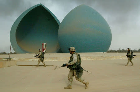 U.S. Marines from Lima Company, a part of a 7-th Marine Regiment, walk in front of the Martyrs Monument, during the operation of securing the centre of Baghdad, Iraq April 9, 2003. REUTERS/Oleg Popov/Files