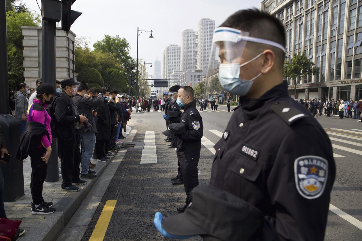 People and policemen bow their heads during a national moment of mourning for victims of coronavirus in Wuhan in central China's Hubei Province on Saturday, April 4, 2020. With air raid sirens wailing and flags at half-staff, China on Saturday held a three-minute nationwide moment of reflection to honor those who have died in the coronavirus outbreak, especially "martyrs" who fell while fighting what has become a global pandemic.