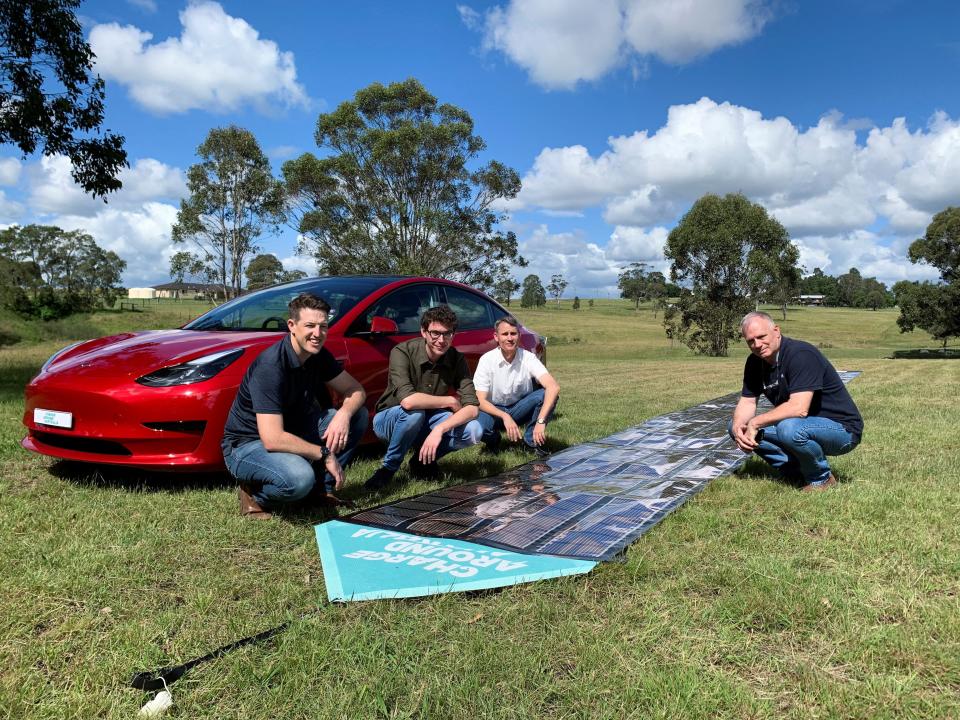 Charge Around Australia project lead and inventor of 'printed solar' panels Paul Dastoor and team members next to a printed solar panel and Tesla car, in Gosforth, Australia