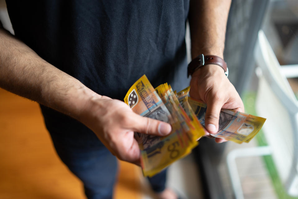 Young male counting Australian $50 notes. (Source: Getty)