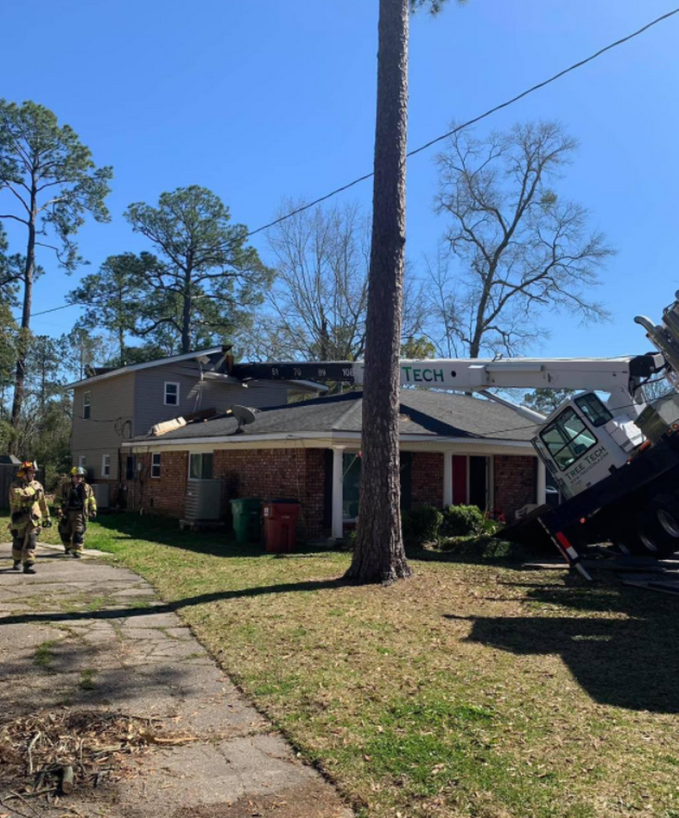 A crane attached to a tree-trimming service truck smashed into the top of a nearby home.