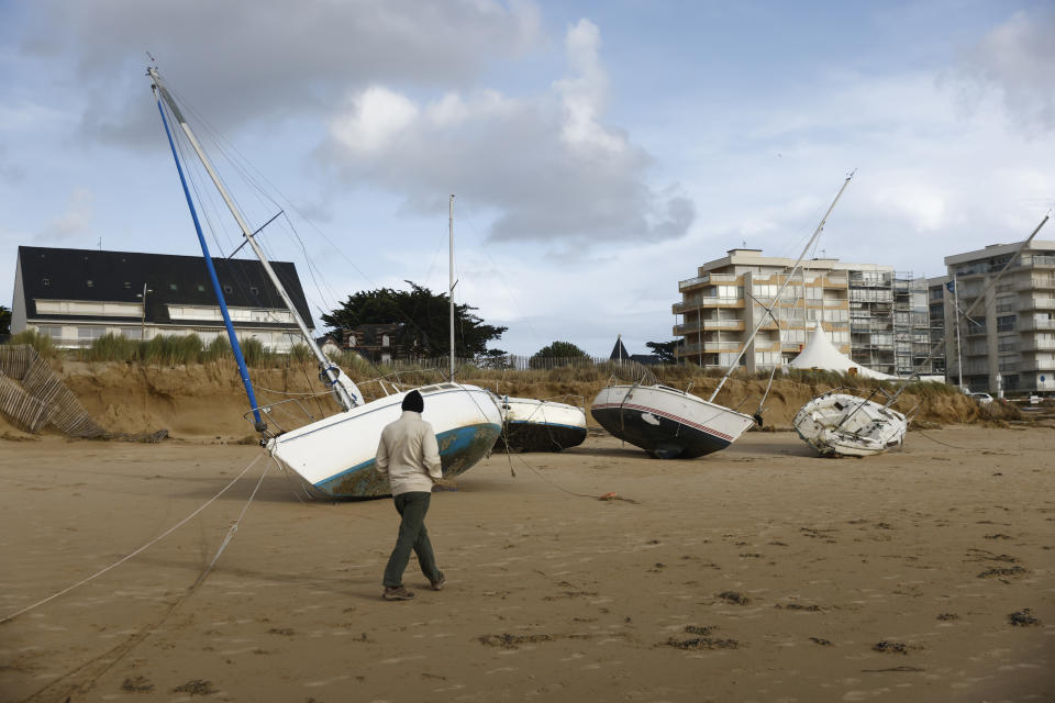 A man walks by washed ashore boats on the beach of Pornichet, Brittany, Thursday, Nov. 2, 2023. Winds up to 180 kilometers per hour (108 mph) slammed the French Atlantic coast overnight along with violent rains and huge waves, as Storm Ciaran uprooted trees, blew out windows. (AP Photo/Jeremias Gonzalez)