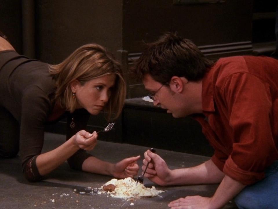 Jennifer Aniston as Rachel and Matthew Perry as Chandler, eating a cheesecake off the floor on season seven, episode 11 of "Friends."