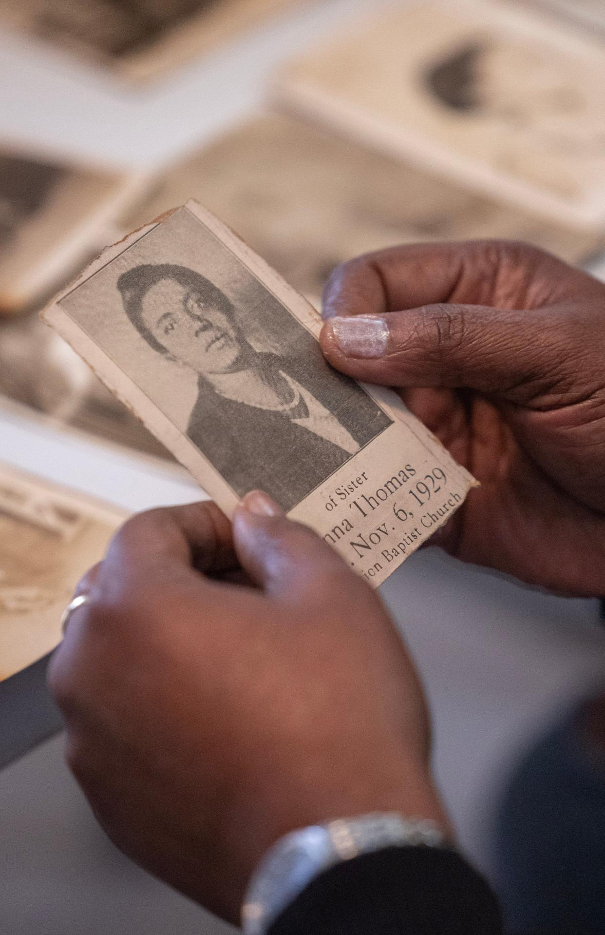 Deborah Johnson-Graham holds a newspaper clipping of a family member that a team from Habitat for Humanity found hidden away in her family's former home in Canton.