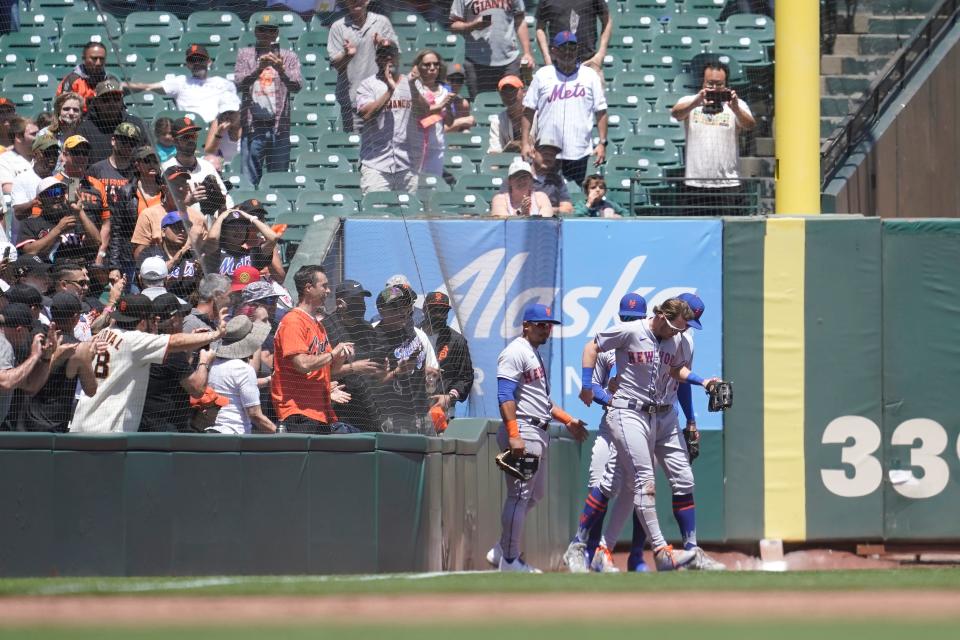 New York Mets right fielder Jeff McNeil, bottom right, is assisted by teammates after catching a foul ball hit by San Francisco Giants' Donovan Walton during the third inning of a baseball game in San Francisco, Wednesday, May 25, 2022.