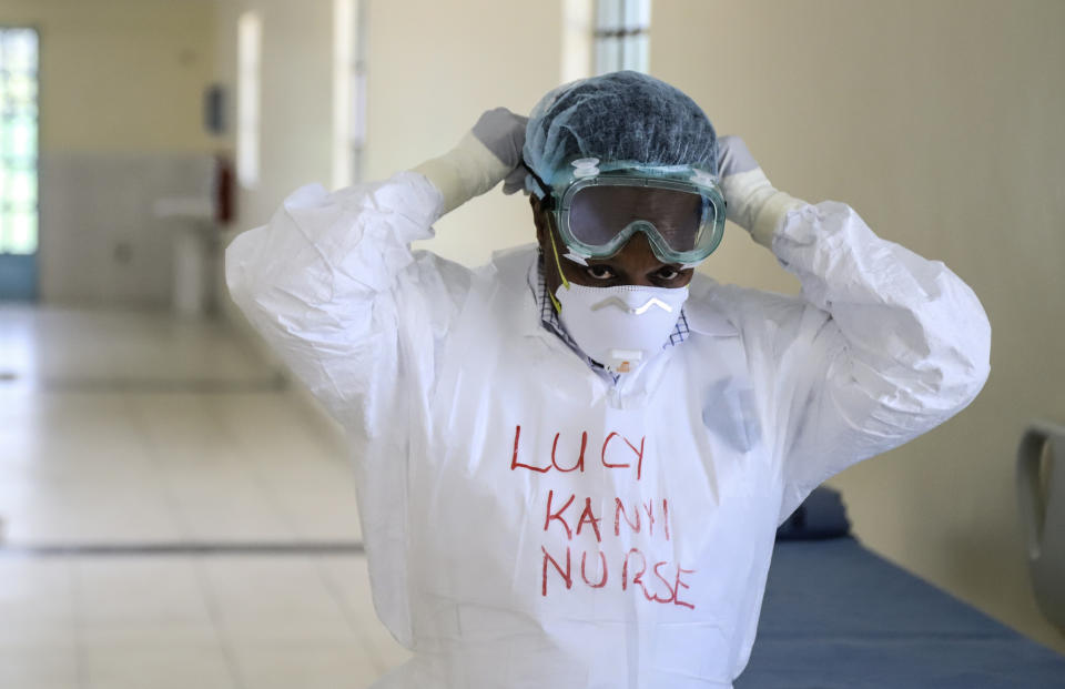 FILE - In this March 6, 2020, file photo, Kenyan nurse Lucy Kanyi, with her name written on her protective clothing so she can be recognized when wearing it, demonstrates protective equipment to members of the media, during a visit to the recently completed infectious disease unit of Kenyatta National Hospital, located at Mbagathi Hospital, in the capital Nairobi, Kenya. Diaspora medical groups around the world are scrambling for ways to help combat the coronavirus back home, where they might be more needed than ever before. (AP Photo/Patrick Ngugi, File)