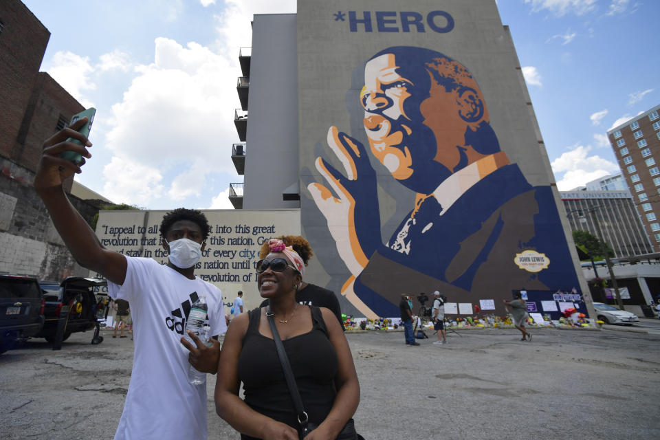 FILE - In this July 19, 2020, file photo, people gather at a makeshift memorial near the home of Rep. John Lewis, D-Ga., in Atlanta. Lewis, who died Friday at age 80, was the youngest and last survivor of the Big Six civil rights activists who organized the 1963 March on Washington, and spoke shortly before the group's leader, Rev. Martin Luther King Jr., gave his "I Have a Dream" speech to a vast sea of people. (AP Photo/Mike Stewart)