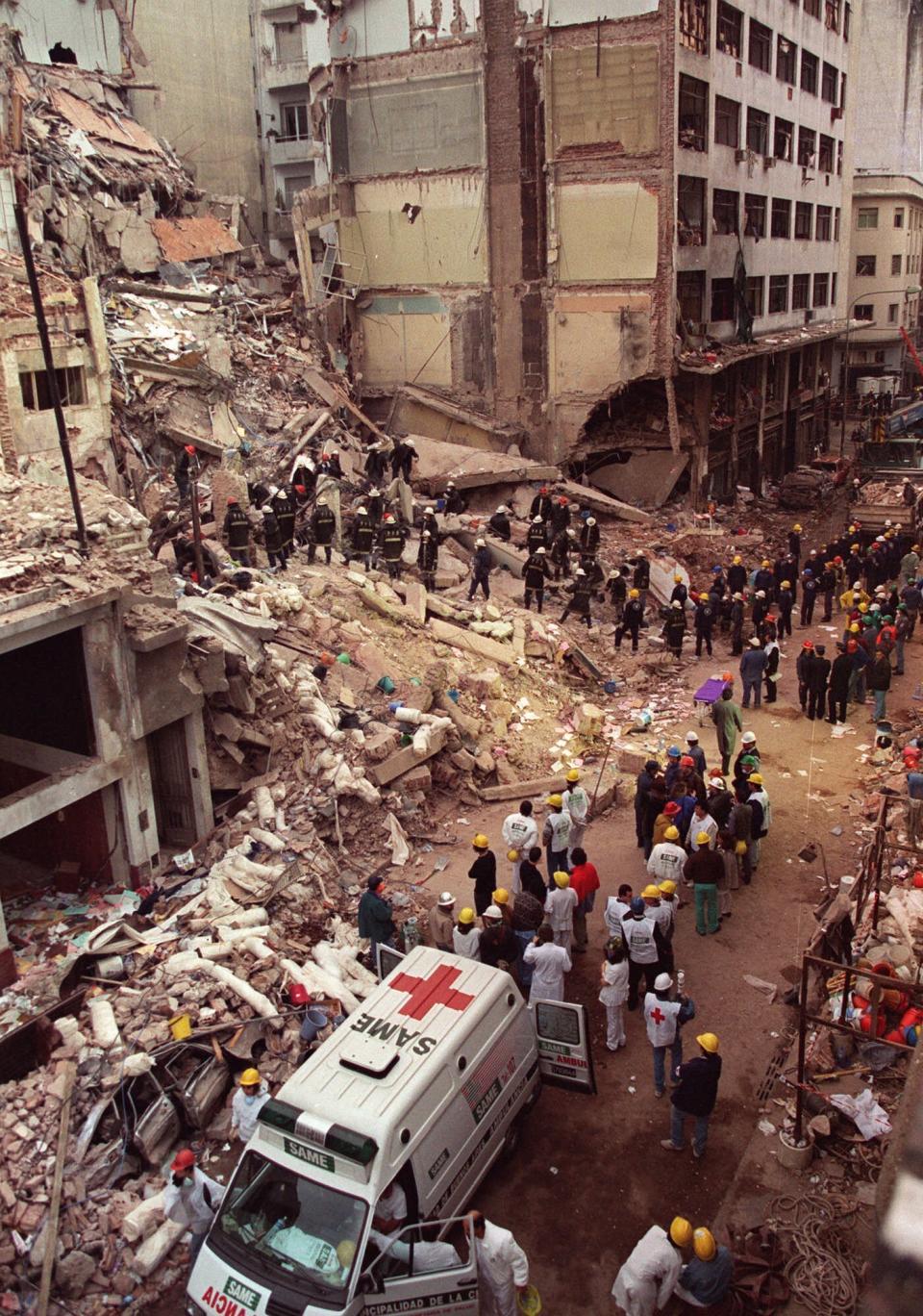 FILE - In this July 18, 1994 file photo, firefighters and rescue workers search through the rubble of the Buenos Aires Jewish Community center after a car bomb destroyed the building, killing 85 people. Argentina announced on Wednesday, July 17, 2019, that it is creating an anti-terrorism database ahead of the 25th anniversary of its worst terror attack. (AP Photo/Alejandro Pagni, File)