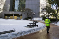 A worker walks the path leading to the boarded-up south entrance of the Hennepin County Government Center, Wednesday, Feb. 23, 2021, in Minneapolis, where the trial of former Minneapolis police officer Derek Chauvin is scheduled to begin with jury selection March 8. Chauvin is charged with murder the death of George Floyd during an arrest last May in Minneapolis. (AP Photo/Jim Mone)