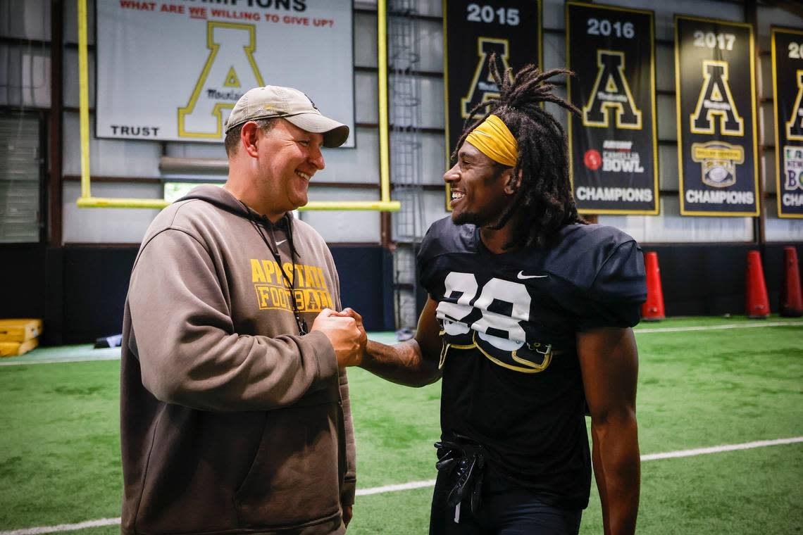 Appalachian State head football coach Shawn Clark jokes with outside linebacker Kesean Brown (28) during an indoor practice in Boone, N.C., Tuesday, Aug. 30, 2022. The Appalachian State Mountaineers football team is preparing to host UNC this weekend.
