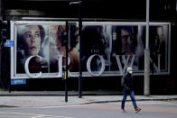 FILE - In this Friday, Nov. 20, 2020 file photo, a man wearing a face mask in London, walks past a billboard advertising 'The Crown' television series about Britain's Queen Elizabeth II and the royal family. Britain’s royal family and television have a complicated relationship. The medium has helped define the modern monarchy: The 1953 coronation of Queen Elizabeth II was Britain’s first mass TV spectacle. Since then, rare interviews have given a glimpse behind palace curtains at the all-too-human family within. (AP Photo/Matt Dunham, File)