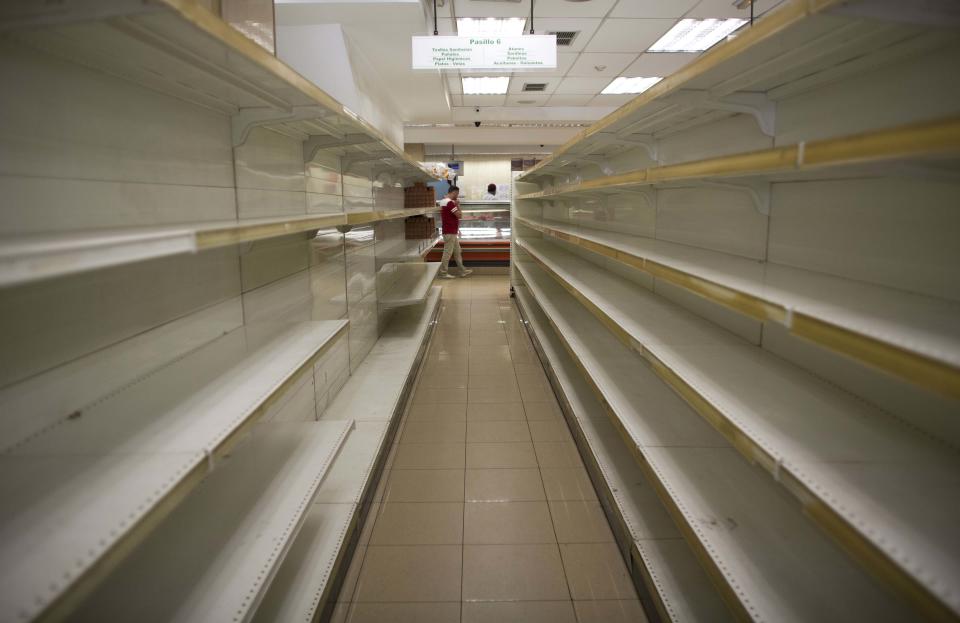 FILE - In this March 23, 2018 file photo, empty shelves stand in a supermarket in Caracas, Venezuela. A new currency with six fewer zeros debuts Friday, Oct. 1, 2021, in Venezuela, whose currency has been made nearly worthless by years of the world's worst inflation. (AP Photo/Ariana Cubillos, File)