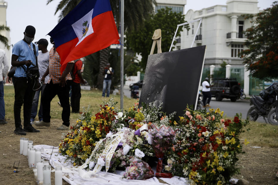 A photo, altered to show the slain Haitian President Jovenel Moise weeping, and a national flag make up part of a memorial outside the presidential palace in Port-au-Prince, Haiti, Wednesday, July 14, 2021, a week after Moise was assassinated in his home.(AP Photo/Joseph Odelyn)