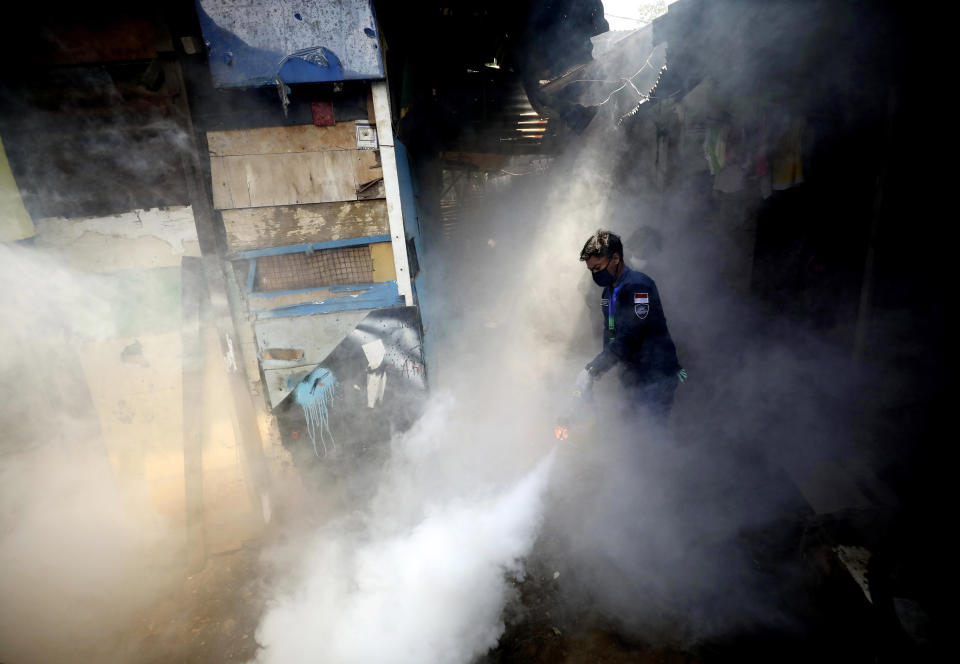 A worker fumigates a slum area to prevent dengue fever outbreak in Jakarta, Indonesia, Wednesday, April 22, 2020. Indonesian President Joko Widodo has banned people from returning to their hometowns to celebrate the Muslim Eid al-Fitr holiday amid warnings from health experts that the country could face an explosion of coronavirus cases unless the government takes stricter measures. (AP Photo/Dita Alangkara)