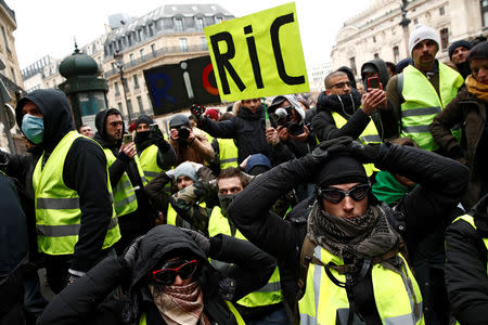 Protesters wearing yellow vests kneel on the street as they gather in front of the Opera House as part of the "yellow vests" movement in Paris, France, December 15, 2018. REUTERS/Christian Hartmann